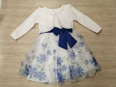 Chaqueta blanca con cierre al cuello y vestido blanco con flores azules y brillos