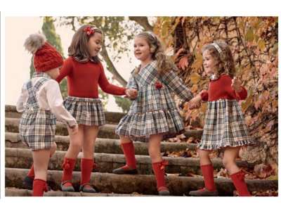 Unas niñas visten los vestidos de cuadros de manga larga en tonos gris,crudo y naranja
