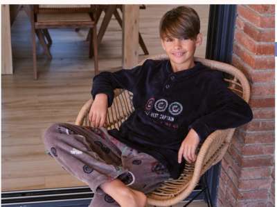 Un niño viste el pijama de coralina en tono azul con gris y dibujo de brújulas