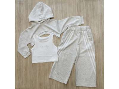 Sudadera corta gris con gorro y pantalón de pata ancha gris con raya blanca. La camiseta es blanca de tirante ancho